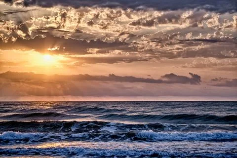 Sunset over the ocean with waves and clouds in the sky Foto stock