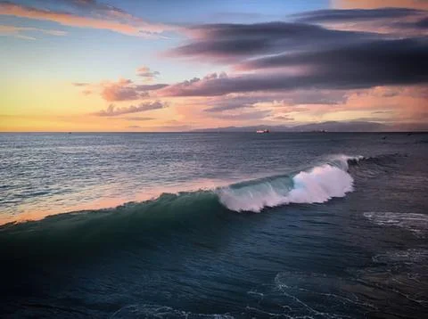 Sunset over ocean with waves and colorful sky Stock Photos