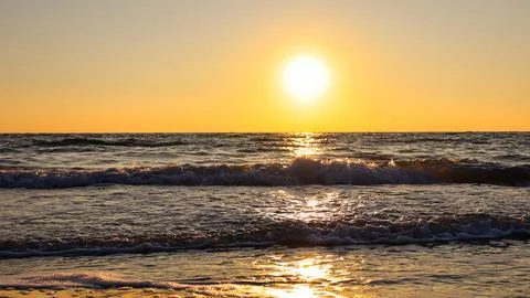 Sunset over the ocean with waves and a clear sky in the background Stock Photos
