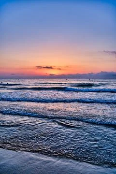 Sunset over ocean waves at a beach scene with colorful sky during evening hou Foto stock