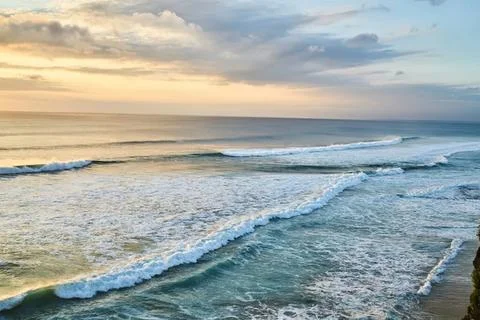 Sunset over ocean waves with cloudy sky and beach Fotos Stock