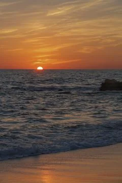 Sunset over ocean waves in coastal area during evening Stock Photos