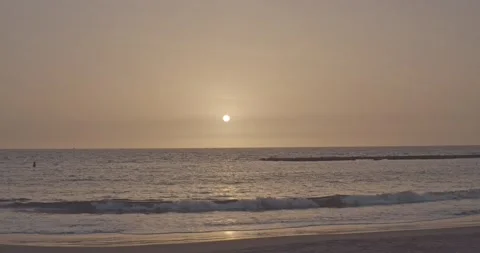 Sunset over ocean, waves gently drenching the sand Stock Footage 136910817