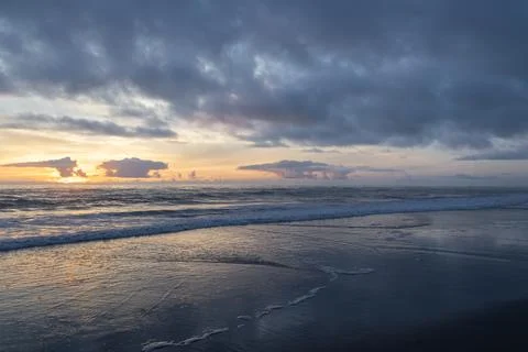Sunset over the ocean with waves gently lapping at the sandy beach in a qui.. Stock Photos