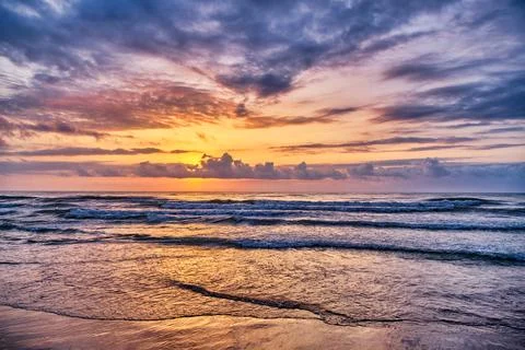 Sunset over ocean waves with vibrant sky colors at beach location Stock Photos