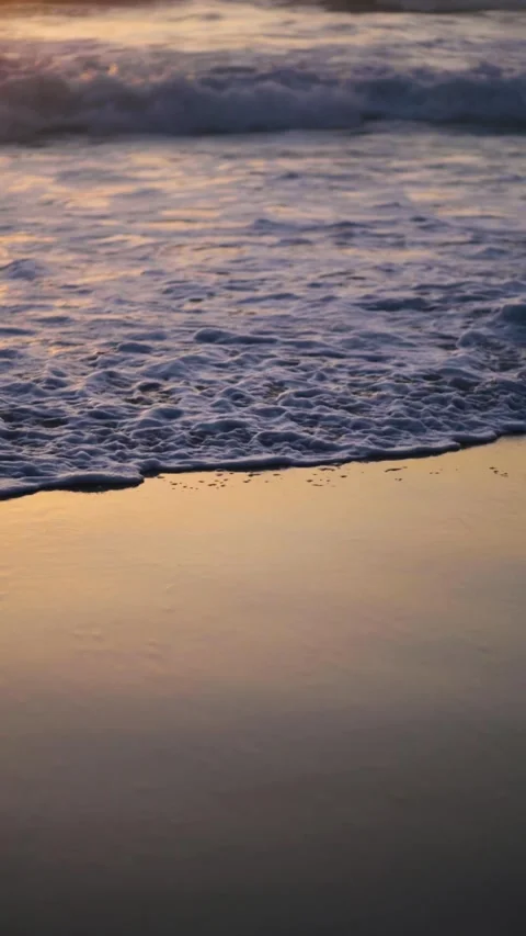 Sunset over the ocean waves washes the sandy beach. Vertical video 스톡 동영상 244341374
