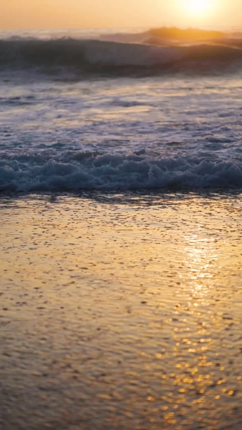 Sunset over the ocean waves washes the sandy beach. Vertical video Stock Footage 244584604