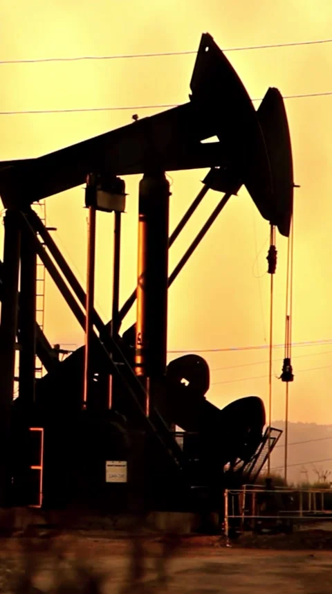 Sunset Over Oil Pump Jack in Silhouette Against Vibrant Sky Stock Footage 306866106