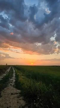 Sunset over open field with dark sky and dramatic clouds Stock Photos