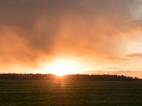 Sunset over open field with dramatic orange sky and clouds Stock Photos