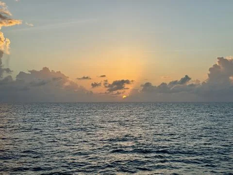 Sunset Over Open Ocean with Dramatic Clouds and Golden Horizon Stockfoto's