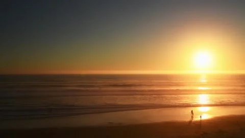 Sunset over the Pacific Ocean coast with silhouetted people on the shore Stock Footage 278193333