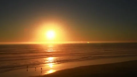 Sunset over the Pacific Ocean coast with silhouetted people playing in the water Stock Footage 278193335