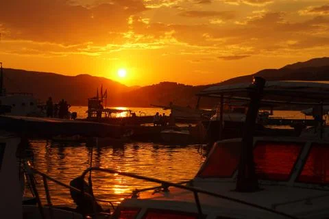 Sunset over a pier full of small fishing boats Foto stock