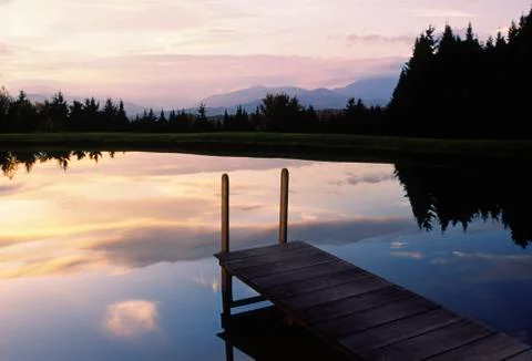 Sunset over a pond and dock in vermont Stock Photos