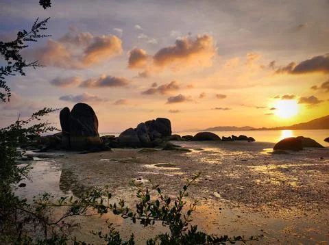 Sunset over a quiet beach with rocks and low tide in a coastal area. Koh Sa.. Stock Photos