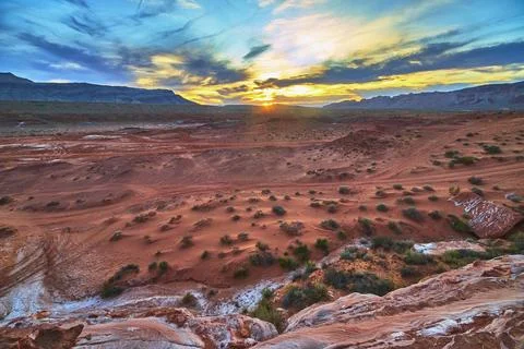 Sunset Over Red Sandstone Desert Landscape With Mountains And Dramatic Sky Stock Photos
