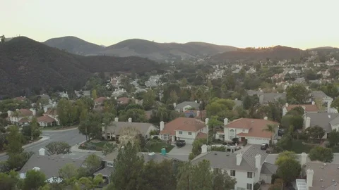 The Sunset over a residential area in between green mountains Video stock 98186918