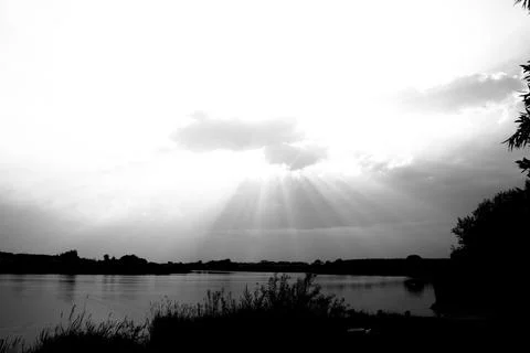 Sunset over the river. Black and white photo of the sun. Stock Photos