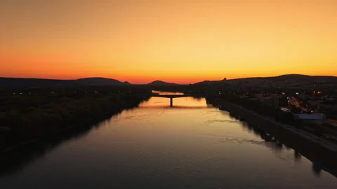 Sunset over the river with a bridge and hills in the background during evening Stock Footage 344234736