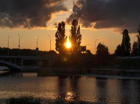 Sunset over river with bridge and silhouetted trees 写真素材