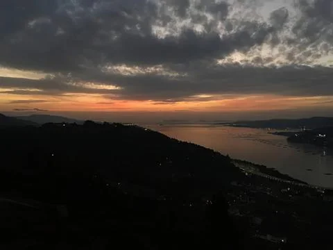 Sunset over river with cloudy sky and hilly landscape Stock Photos