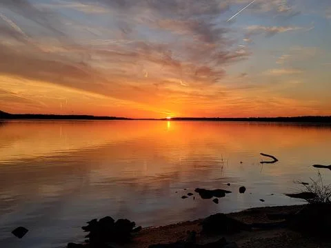 Sunset over a river with a few clouds in the sky and calm reflecting waters Stock Photos