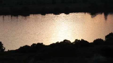 Sunset over river with green field, drone shot Video stock 303539851