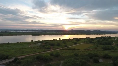 Sunset over river with green field, drone shot Video stock 303539887