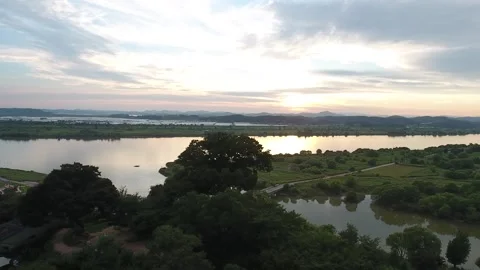 Sunset over river with green field, drone shot Video stock 303539888