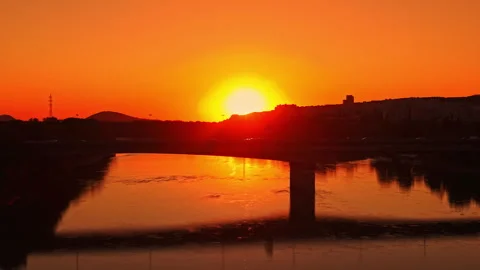 Sunset over a river with reflections along the shore and hills in the background Stock Footage 344236122