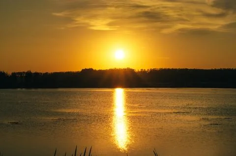 Sunset over the river, the sun is reflected in the water as a column of light Stock Photos