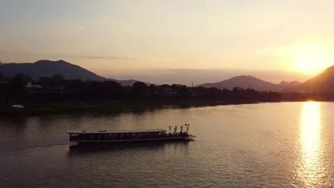 Sunset over river with traditional boat and mountains in the background Video stock 344450830