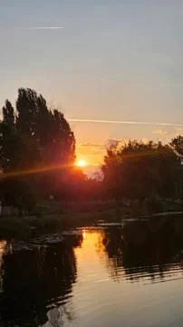Sunset over river with trees and reflection in water Stock Photos