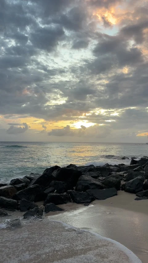 Sunset over rocky Barbados beach with sailboat and dramatic clouds Stock Footage 337108412