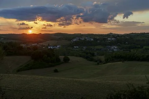 Sunset over rolling hills, dramatic clouds, small village, fields, golden h.. Stock Photos