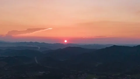 Sunset over rolling mountain ranges with warm golden hour light and clouds Stock Footage 342327442