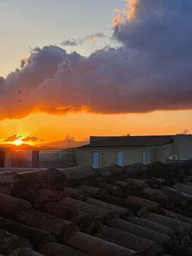 Sunset Over Rooftops with Clouds Stock Photos
