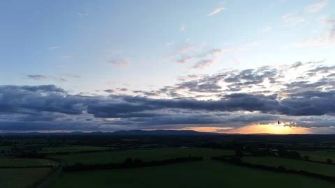 Sunset Over Rural Fields with Dramatic Cloudy Sky Aerial View Foto stock