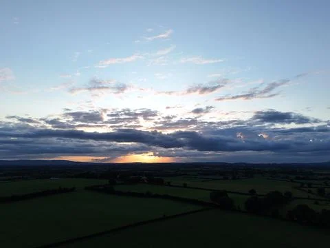 Sunset Over Rural Fields with Dramatic Cloudy Sky Aerial View Foto stock