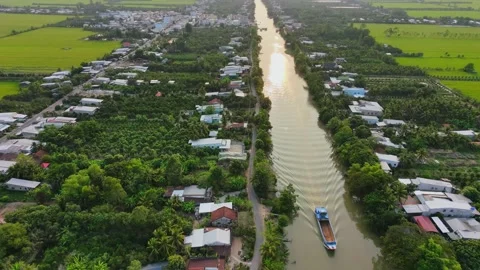 Sunset over rural river with a cargo boat leaving water wakes, Vietnam Vídeos de archivo 335744613