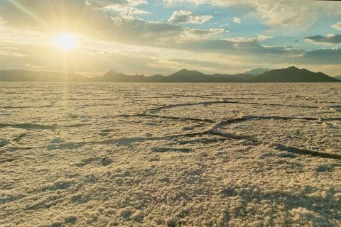 Sunset over salt flat with mountain backdrop in a vast, open landscape Stock Photos
