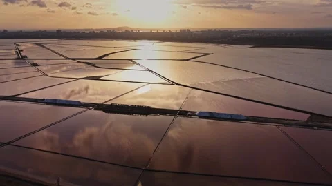 Sunset over salt pans and water bodies near the city skyline 動画素材 335141927