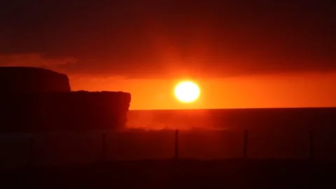 Sunset over the sea and cliffs in Orkney with crashing waves in 4K 動画素材 297991970