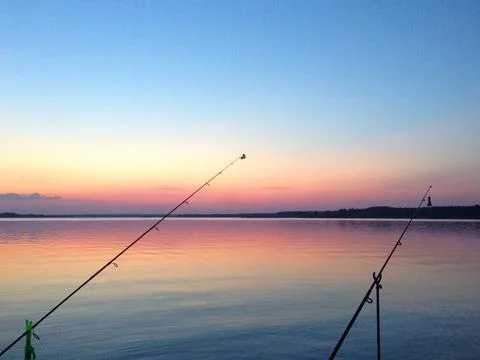 Sunset over the sea on the background of two fishing rods Stock Photos