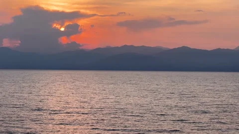 Sunset over the Sea with Clouds and Mountains in Background Stock Footage 316836141