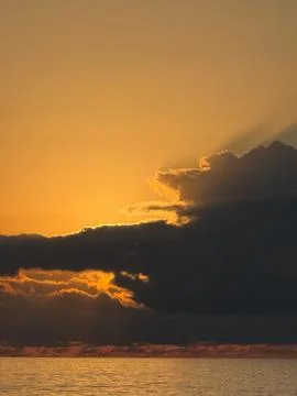 Sunset over the sea with dramatic cloud formations partially covering the sun Foto stock