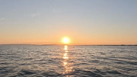 Sunset over the Sea with Gentle Waves and Mountains in the Background Stock Footage 283931078