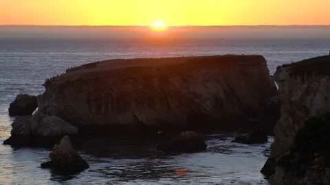 Sunset over the sea at low tide. Rocks, and sky with the sun setting down the ho Stock Footage 168277494