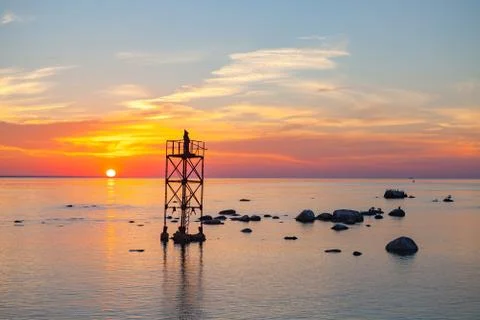Sunset over sea with magic installation of black monk on the tower Stock Photos